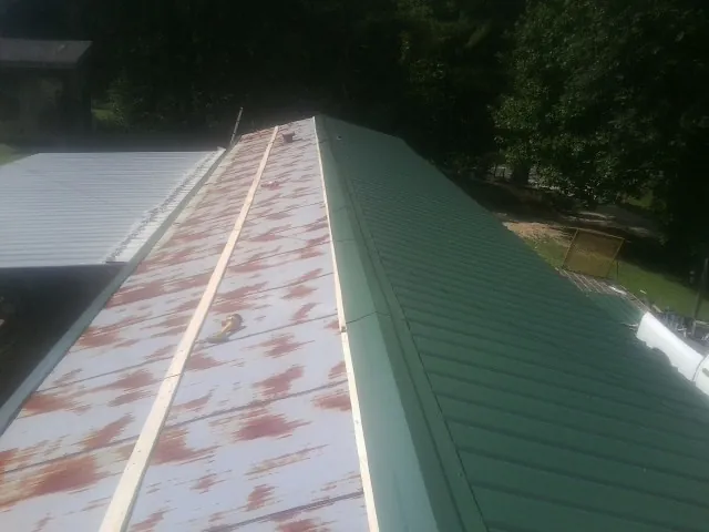 Old rusted panels beside newly installed green metal roofing — Wind Damage Roof Repair by Roofing Brothers in Woodbine